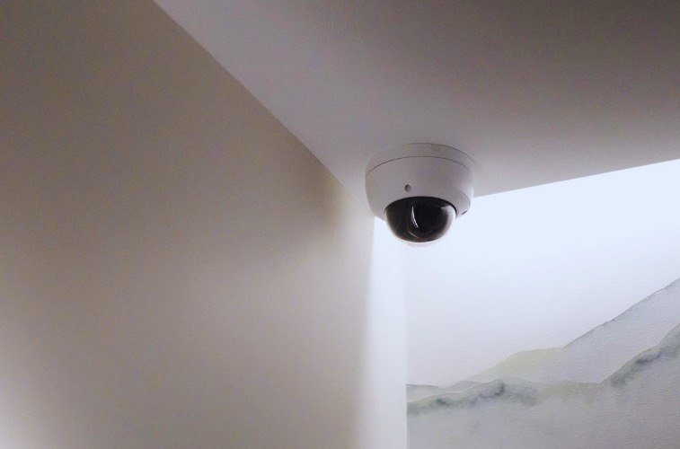 Security Camera Installation for NYC Businesses: What You Need to Know 1 A dome security camera mounted on the ceiling corner above a stairwell.